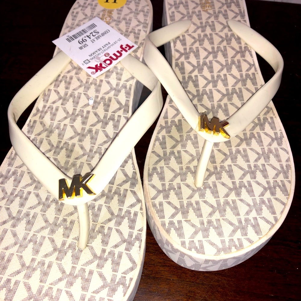 White and beige wedge style flip flops. MK emblem on front.